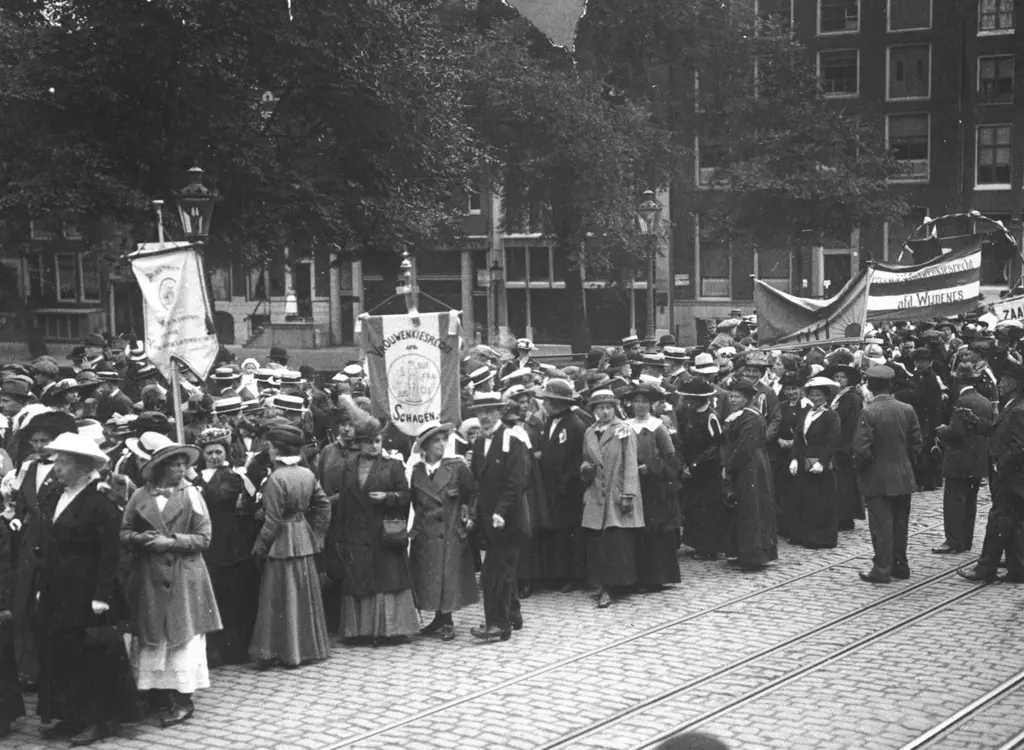Stoet met vrouwen en een paar mannen, met aantal vaandels.