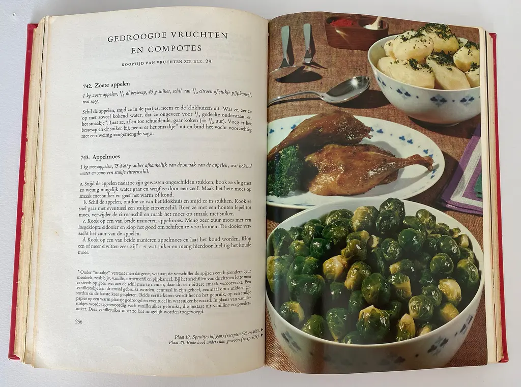 Twee bladzijdes uit een kookboek uit 1925. Op de linkerbladzijde is een recept te lezen van gedroogde vruchten en compotes en op de rechterbladzijde een foto van spruitjes, gebraden kip en gekookte aardappelen op een gedekte tafel.
