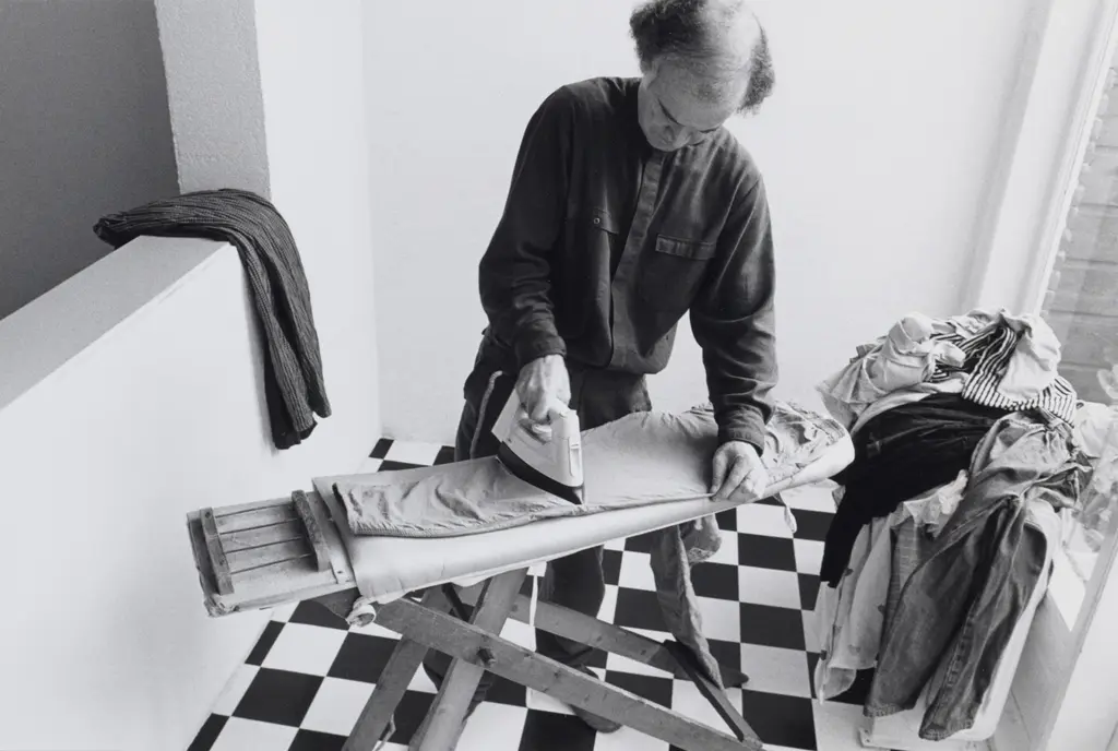 Man staat broek te strijken op een strijkplank
