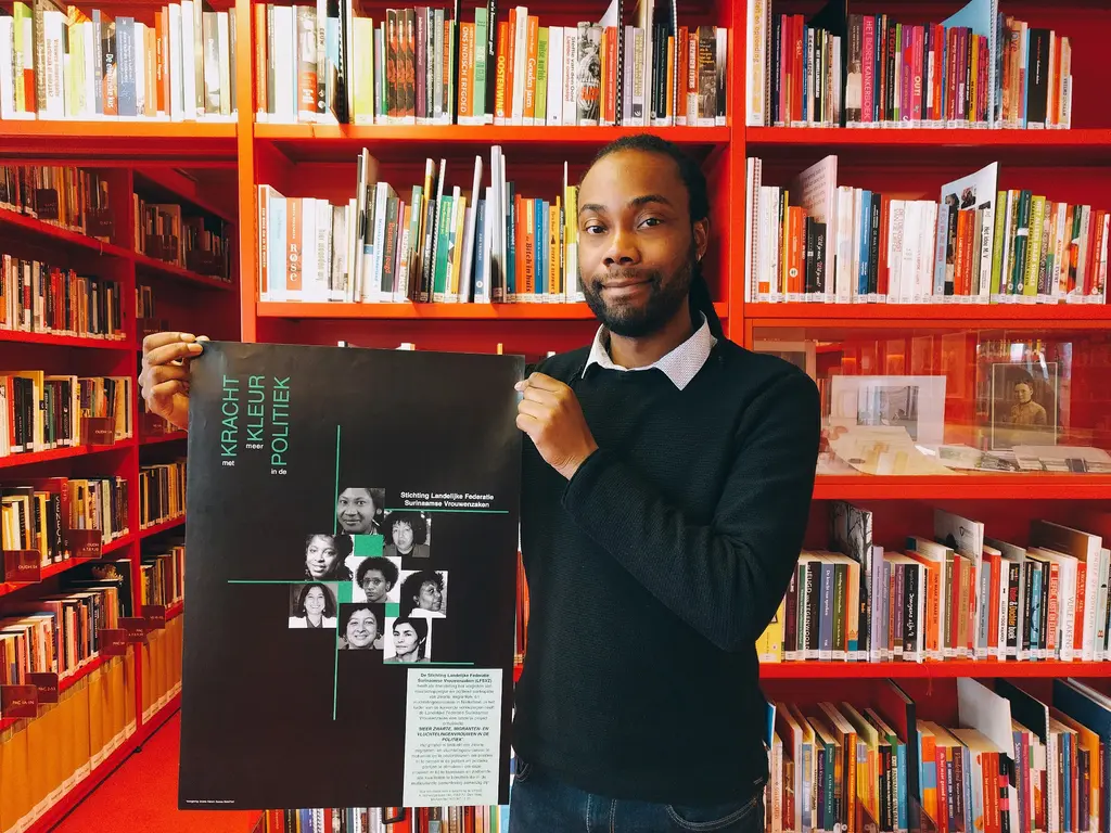 Simion Blom met een poster van de Stichting Landelijke Federatie Surinaamse Vrouwenzaken