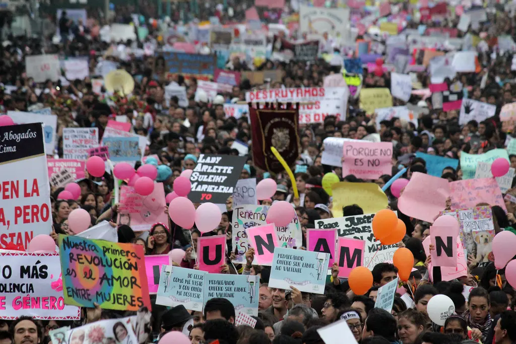 Protest van #NiUnaMenos in 2016 in Peru. Grote groep mensen met roze balonnen, spandoeken en protestborden