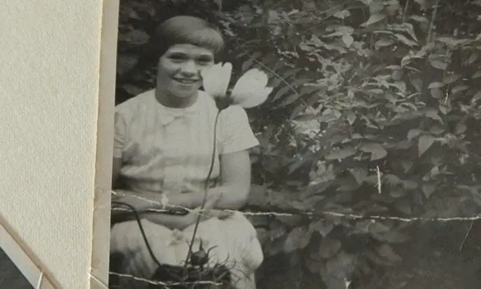 Foto van meisje met kort haar met voor haar een bloeiende bloem