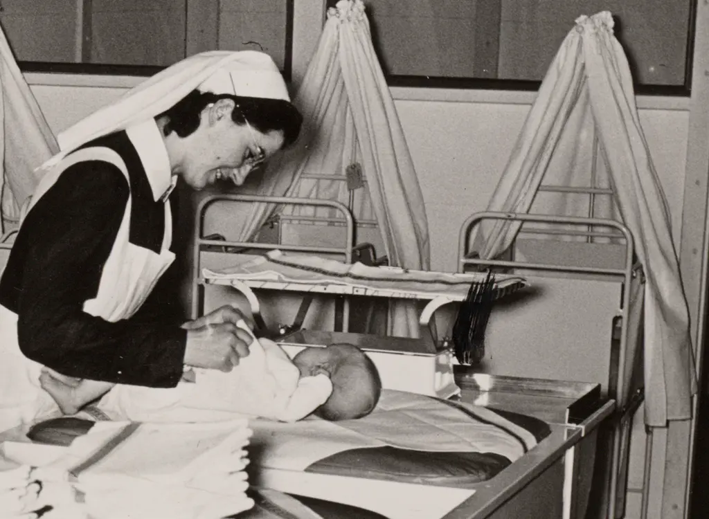 verpleegkundige-tilt-baby-uit-wieg_1950_rotterdams-nieuwsblad_collectie-iav-atria.jpg