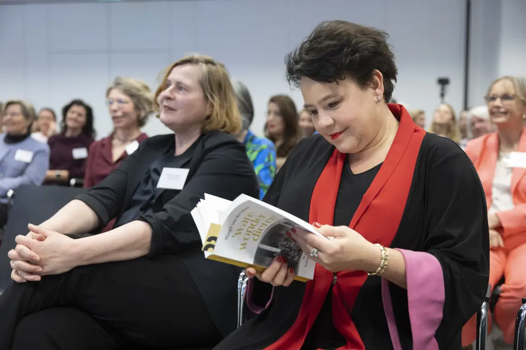 VNG-voorzitter en burgemeester van Utrecht Sharon Dijksma zit naast Atria-directeur Karin van der Heiden en bladert in het boek 'Ware wonderdieren'. Foto door Henriëtte Guest, 2026.