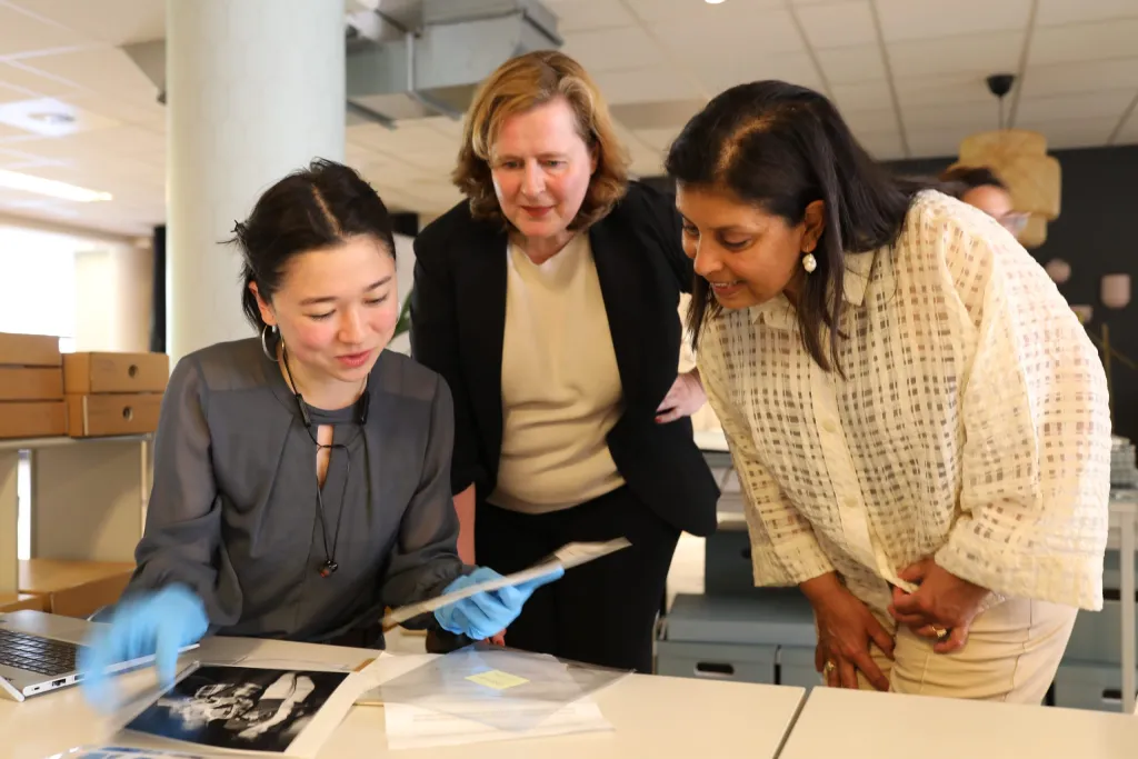 Stagiair Mia Lodder laat een foto uit het beeld- en geluidarchief zien aan Mariëlle Paul (rechts) en Karin van der Heiden (midden)