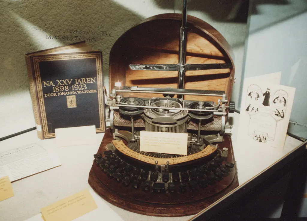 Halfronde typemachine met bruine kap. Ernaast staat een boek door Johanna W.A. Naber