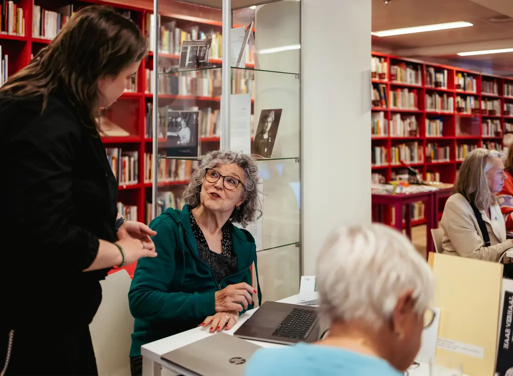 Deelnemer aan WikiVrijdag in gesprek met Wikipediaan in studiezaal van Atria